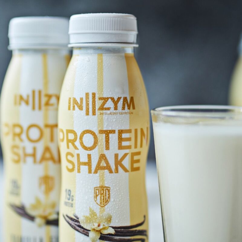 IN2ZYM Protein Shake Vanilje 250 ml. flaske foran et glas mælk