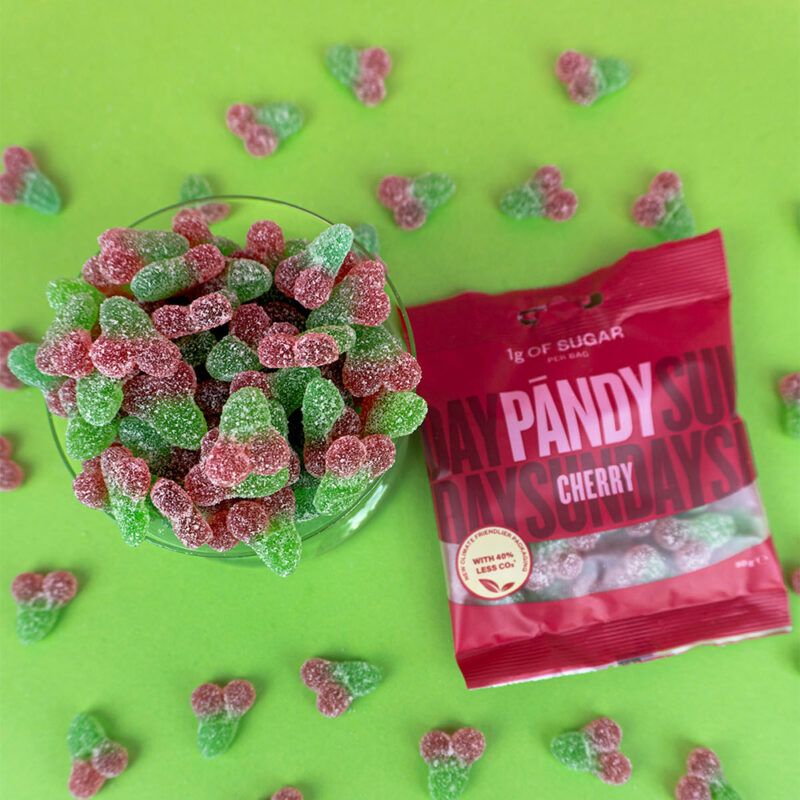 Pandy Candy Cherry løst slik liggende på en grøn baggrund og en pose